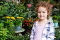 Cheerful cute child girl with curly hair staying in the flower shop Royalty Free Stock Photo