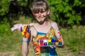 Cheerful cute girl playing with bright paints in the park