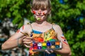 Cheerful cute girl playing with bright paints in the park