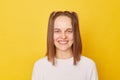 Cheerful cute happy smiling funky teenage girl with ponytails in jumper posing isolated over yellow background looking at camera Royalty Free Stock Photo