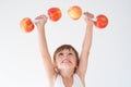 Cheerful cute kid lifting dumbbells made from apples