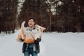 Cheerful cute laughing and smiling guy in jeans clothes with dog border collie red on his hands in snowy forest. concept Royalty Free Stock Photo