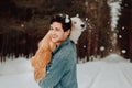 Cheerful cute laughing and smiling guy in jeans clothes with dog border collie red on his hands in snowy forest. concept Royalty Free Stock Photo