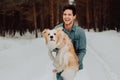 Cheerful cute laughing and smiling guy in jeans clothes with dog border collie red on his hands in snowy forest. concept Royalty Free Stock Photo