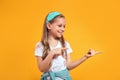 Cheerful cute little girl pointing on copy space at side on yellow background Royalty Free Stock Photo