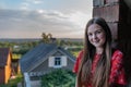 Cheerful cute teen girl with red loose hair in dress looking at the camera while siitin in the window of an unfinished