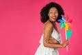 Cheerful cute young african american curly woman with windmill flower enjoy free time, holiday