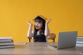 A cheerful and cute young Asian girl holding a book over her head, smiling at the camera Royalty Free Stock Photo