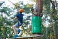 Cheerful cute young boy in blue t shirt and orange helmet in adventure rope park at sunny summer day. Active lifestyle, sport Royalty Free Stock Photo