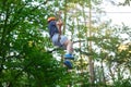 Cheerful cute young boy in blue t shirt and orange helmet in adventure rope park at sunny summer day. Active lifestyle, sport Royalty Free Stock Photo