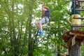 Cheerful cute young boy in blue t shirt and orange helmet in adventure rope park at sunny summer day. Active lifestyle, sport Royalty Free Stock Photo