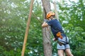 Cheerful cute young boy in blue t shirt and orange helmet in adventure rope park at sunny summer day. Active lifestyle, sport Royalty Free Stock Photo