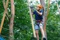 Cheerful cute young boy in blue t shirt and orange helmet in adventure rope park at sunny summer day. Active lifestyle, sport, Royalty Free Stock Photo