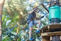 Cheerful cute young boy in blue t shirt and orange helmet in adventure rope park at sunny summer day. Active lifestyle, sport Royalty Free Stock Photo