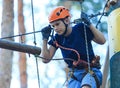 Cheerful cute young boy in blue t shirt and orange helmet in adventure rope park at sunny summer day. Active lifestyle, sport, Royalty Free Stock Photo