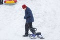 Cheerful cute young boy in orange hat and blue jacket holds tube on snow, has fun, smiles. Teenager on sledding in winter park Royalty Free Stock Photo