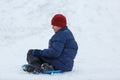 Cheerful cute young boy in orange hat and blue jacket holds tube on snow, has fun, smiles. Teenager on sledding Royalty Free Stock Photo