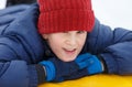 Cheerful cute young boy in orange hat red scarf and blue jacket holds tube on snow, has fun, smiles. Royalty Free Stock Photo