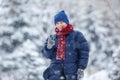 Cheerful cute young boy in orange hat red scarf and blue jacket holds tube on snow, has fun, smiles. Teenager on sledding Royalty Free Stock Photo