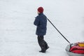 Cheerful cute young boy in orange hat red scarf and blue jacket holds tube on snow, has fun, smiles. Teenager on sledding Royalty Free Stock Photo