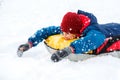 Cheerful cute young boy in orange hat red scarf and blue jacket holds tube on snow, has fun, smiles. Teenager on sledding Royalty Free Stock Photo