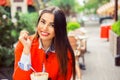 Cheerful cute young woman sitting and drinking shake cocktail in outdoor cafe Royalty Free Stock Photo