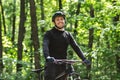 Cheerful cyclist posing with bike over forest background