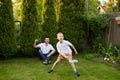 A cheerful dad on the street supports his son. A boy is playing badminton in a white T-shirt Royalty Free Stock Photo