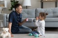 Cheerful daddy and happy preschool daughter kid playing tea party