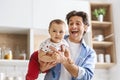 Cheerful daddy riding his baby son like plane, kitchen interior