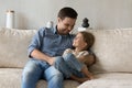 Cheerful daddy tickling and cuddling happy little daughter kid