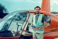 Cheerful dark-haired volunteer with wide smile standing near helicopter