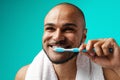 Cheerful dark-skinned male brushing his teeth against turquoise background Royalty Free Stock Photo