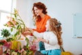 Cheerful daughter having fun while looking at flowers with mom