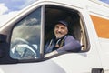 Cheerful delivery driver looking out the window of the white cargo van vehicle, delivering goods by car Royalty Free Stock Photo