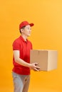 Cheerful delivery man. Happy young courier holding a cardboard box and smiling while standing against white background Royalty Free Stock Photo