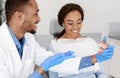 Cheerful dentist educating his patient at dental clinic