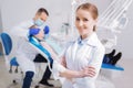 Cheerful dentist smiling while her colleague examining the patient