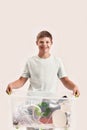 Cheerful disabled boy with Down syndrome smiling at camera while holding a recycling bin full of paper waste, standing Royalty Free Stock Photo