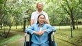 Cheerful disabled granddaughter in a wheelchair with grandfather enjoying nature in the park. Family life on vacation