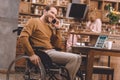 cheerful disabled man in wheelchair talking on smartphone and using laptop