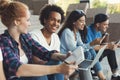 Cheerful diverse teens sitting outdoors and talking Royalty Free Stock Photo