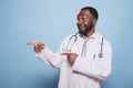 Cheerful doctor gesturing to his right Royalty Free Stock Photo