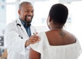 Cheerful doctor offering a patient support. Mature african american doctor touching a patient on the arm. Happy gp Royalty Free Stock Photo