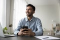 Cheerful dreamy young Indian business leader man holding cellphone Royalty Free Stock Photo