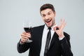 Cheerful drunk businessman drinking red wine and showing ok sign Royalty Free Stock Photo