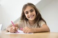 Cheerful early schoolgirl kid drawing pink sketches in colorful pencils Royalty Free Stock Photo