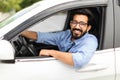 Cheerful eastern guy with glasses driving brand new white auto Royalty Free Stock Photo