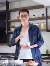 Cheerful efficient male young cook wearing casual cloth working in the kitchen. Young man worker uses whisk and bowl for making Royalty Free Stock Photo