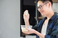 Cheerful efficient male young cook wearing casual cloth working in the kitchen. Young man worker uses whisk and bowl for making Royalty Free Stock Photo